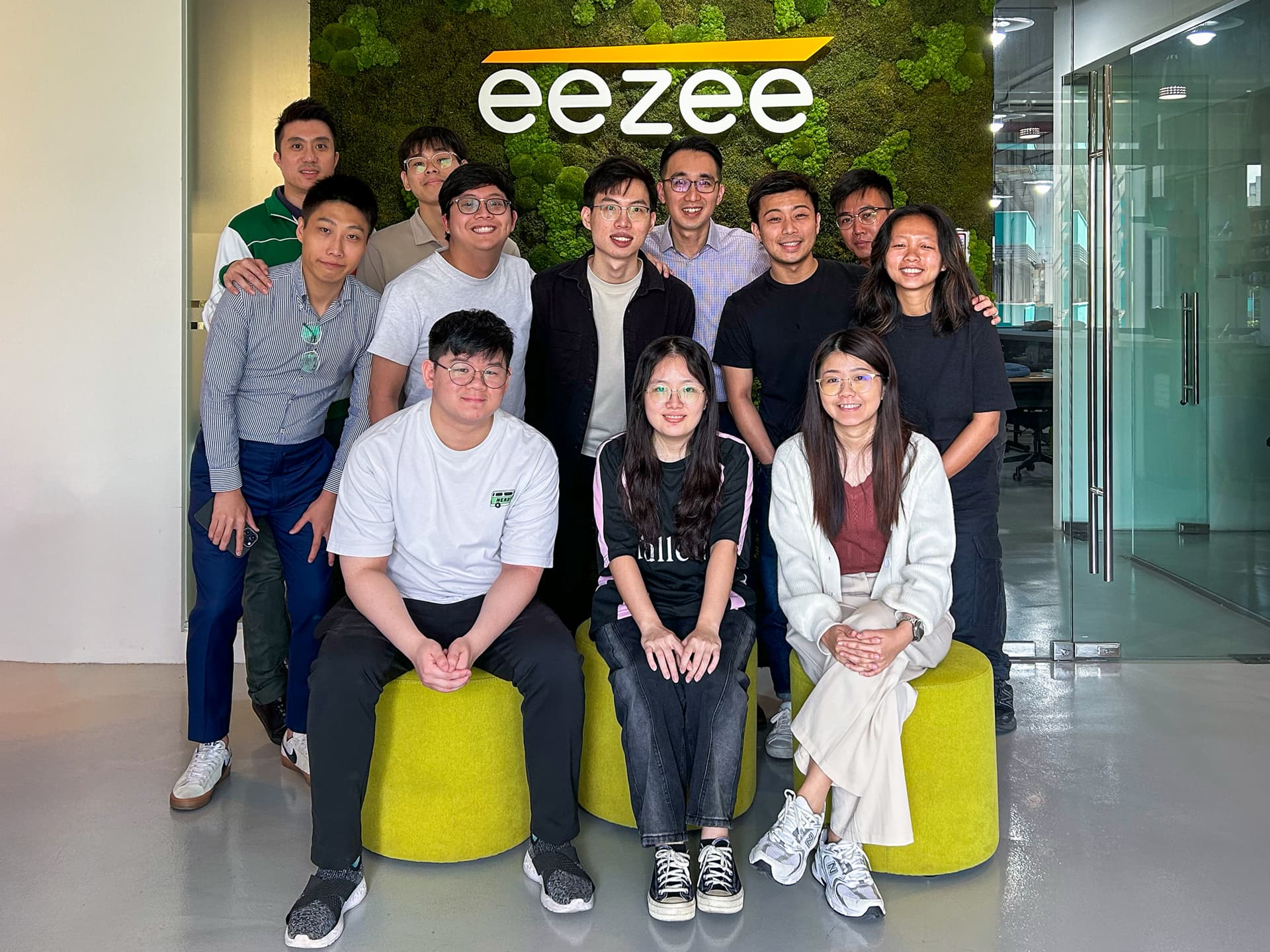 The Eezee team in front of the office logo wall